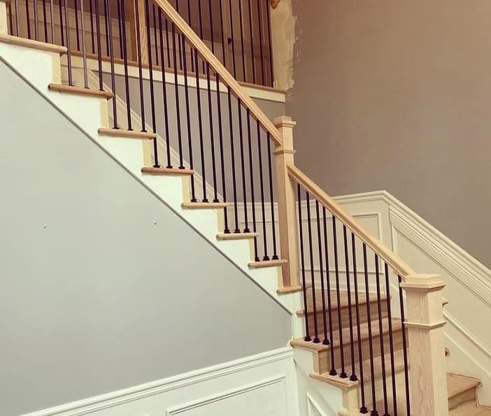 Renovated staircase with white oak handrail, black iron balusters, and hardwood treads