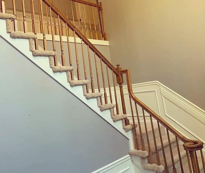 Builder-grade staircase with honey oak spindles and carpet treads