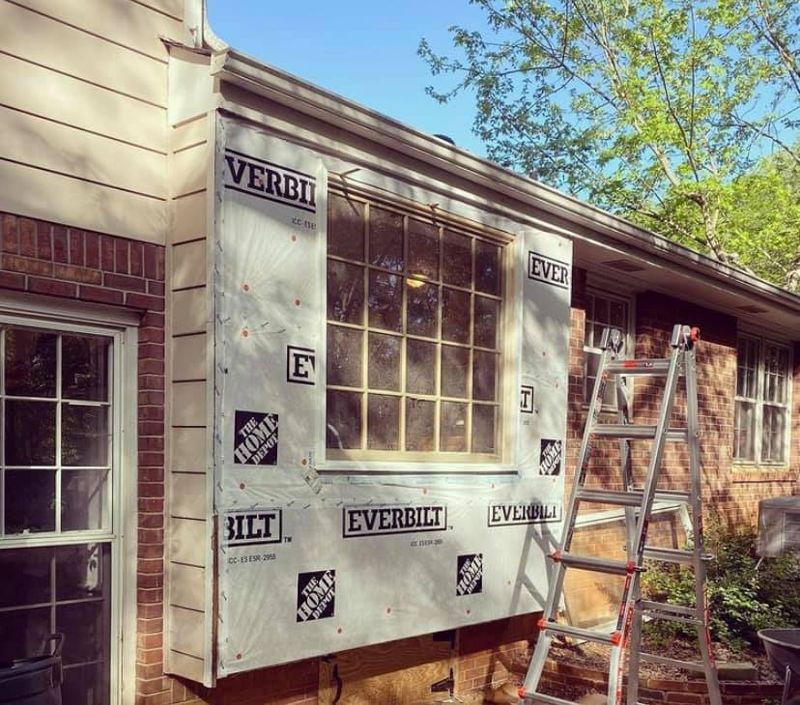 New large grid window set in opening with weather barrier installed, ready for siding