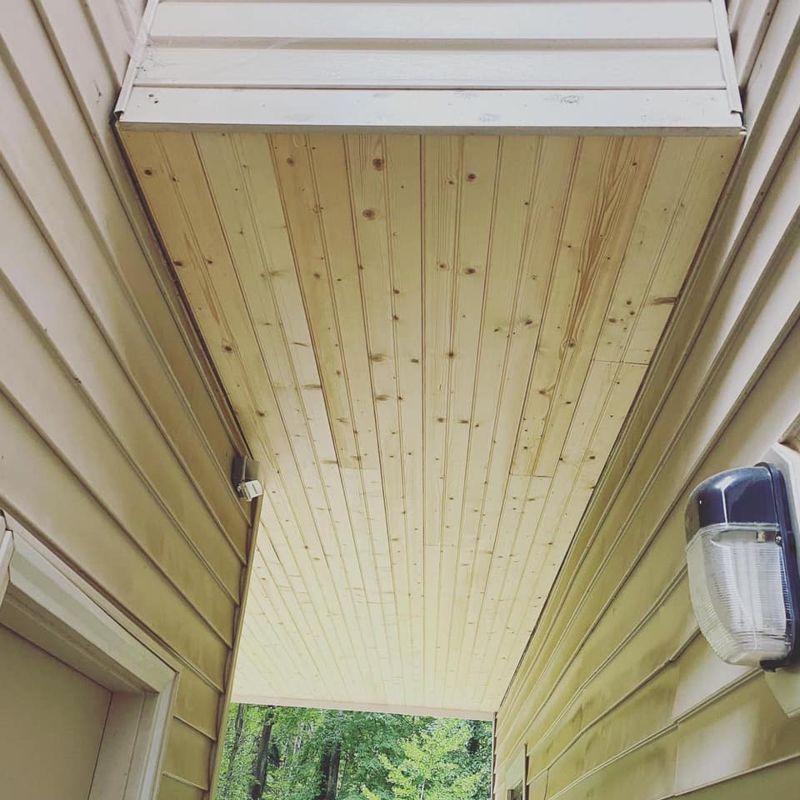 Tongue-and-groove porch ceiling detail with wall sconce and vinyl siding surround