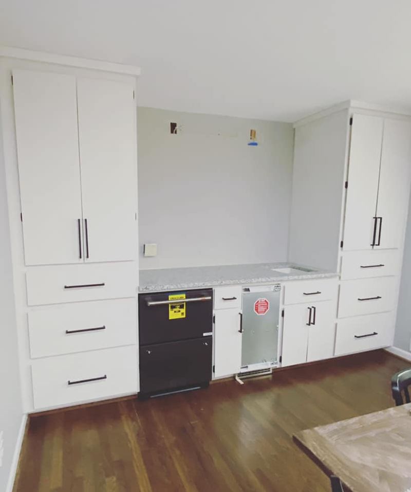 Finished built-in cabinetry with white shaker doors, granite countertop, and integrated appliances