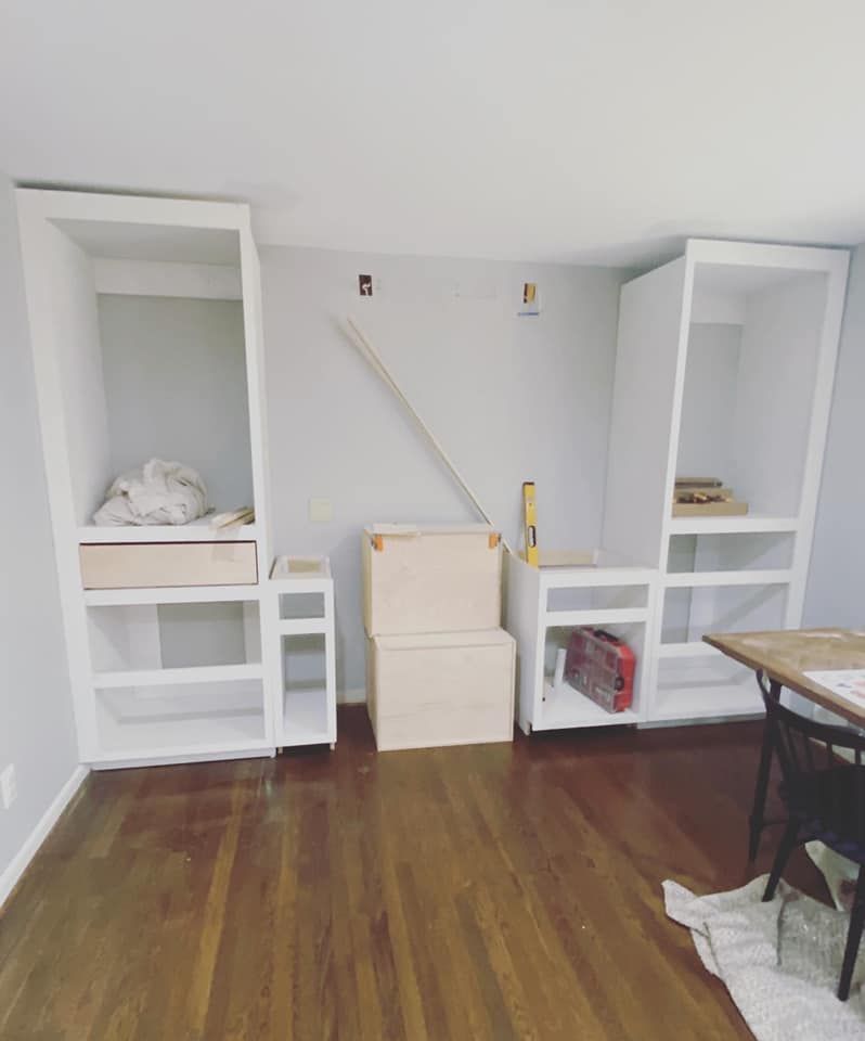 Built-in cabinet framing under construction with shelving towers and unfinished center section