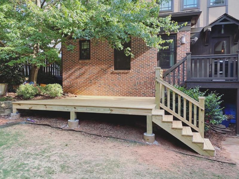 New floating deck with pressure-treated framing on concrete pier footings, side staircase with railing