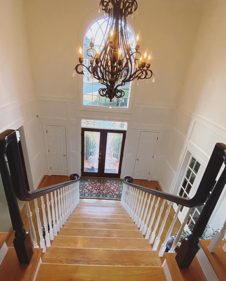 Two-story foyer with grand chandelier, arched window, and leaded glass entry doors