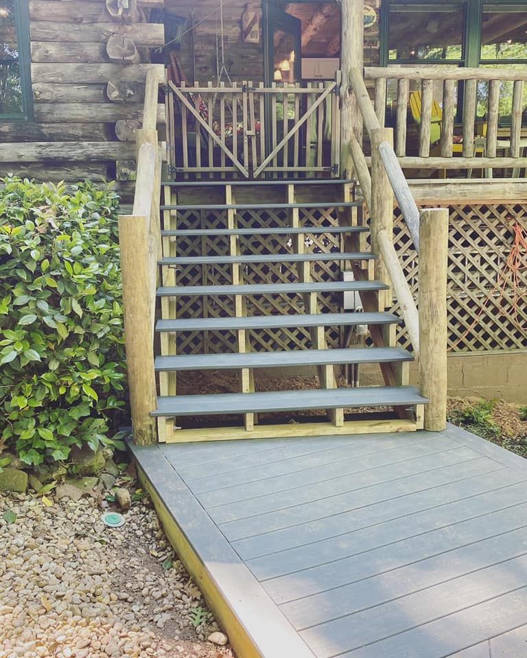 Composite staircase with lattice skirting and log-post handrails leading to log cabin porch