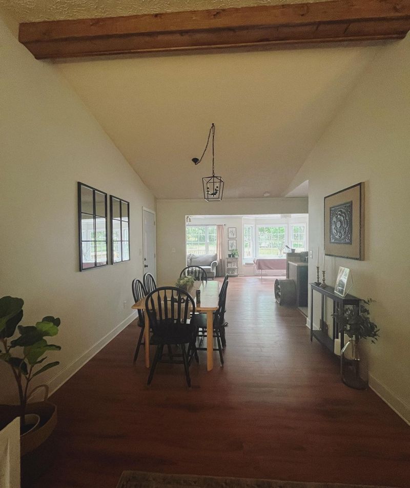 Renovated living area with hardwood floors, cedar beam, and modern pendant light