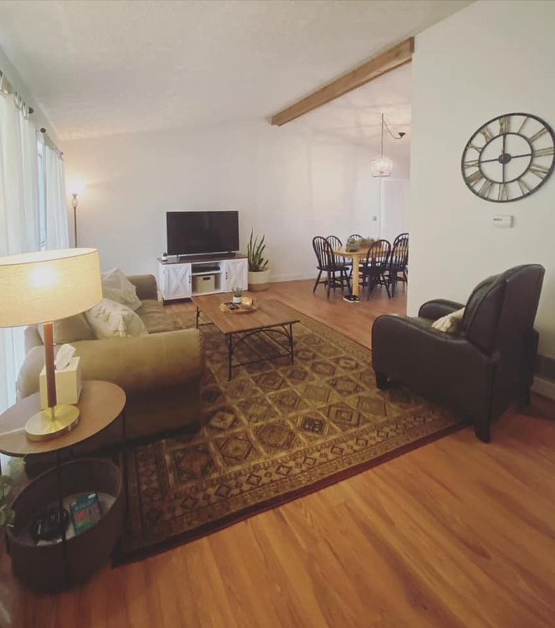 Wide view of finished living and dining area with hardwood floors, cedar beam, and open layout