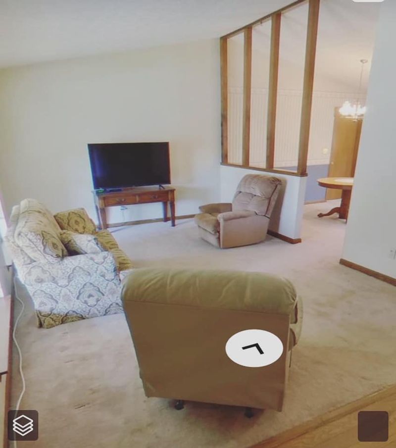 Original living area with worn carpet, wood column divider, and dated layout