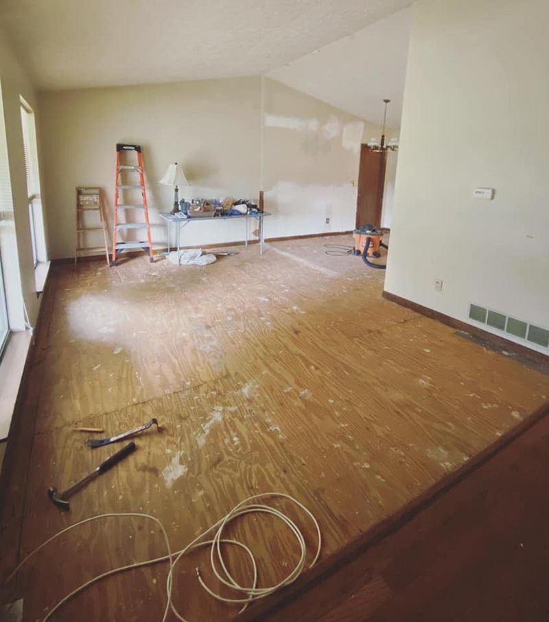 Living area during renovation with exposed plywood subfloor and tools