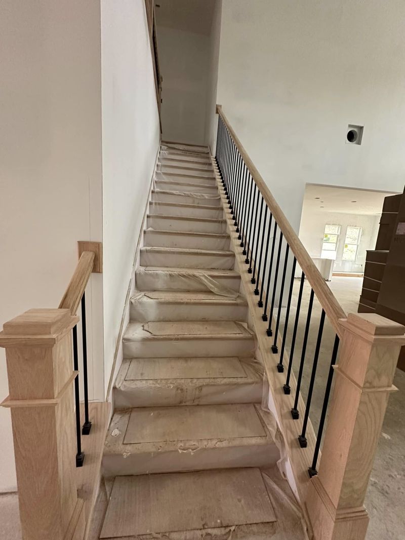 Staircase under construction with protected treads and baluster installation