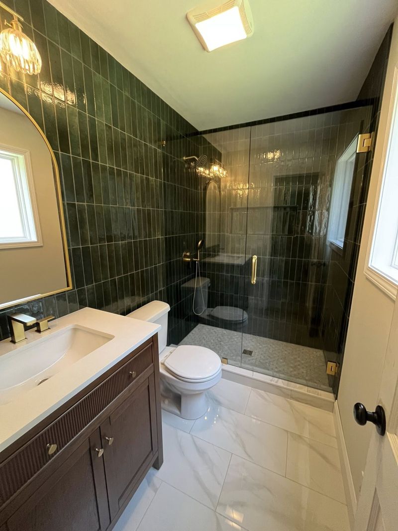 Renovated bathroom with forest green zellige tile and brushed gold fixtures