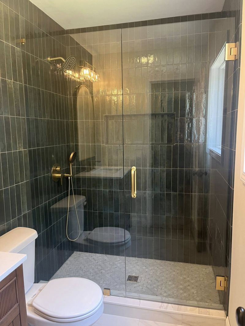 Walk-in shower with frameless glass enclosure, pebble floor, and rain head