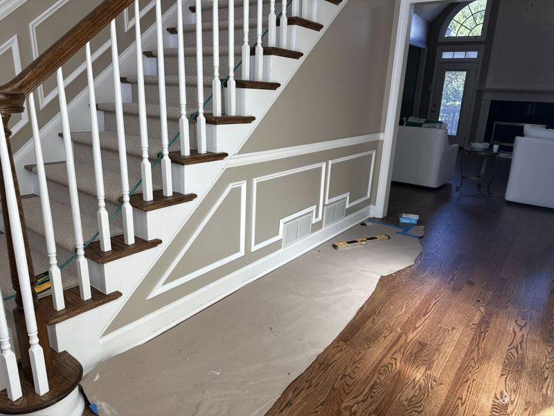 Picture frame wainscoting running the full length of the staircase wall with white turned balusters