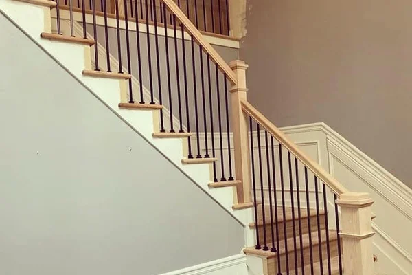 Renovated staircase with white oak handrail, black iron balusters, and hardwood treads