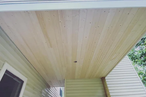Natural knotty pine planks across the porch soffit