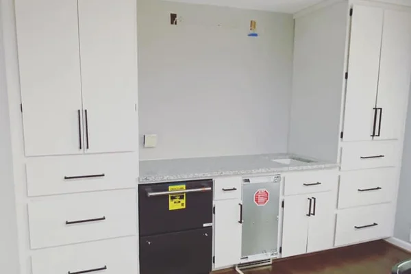 Finished built-in cabinetry with white shaker doors, granite countertop, and integrated appliances