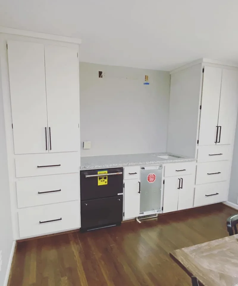 Finished built-in cabinetry with white shaker doors, granite countertop, and integrated appliances