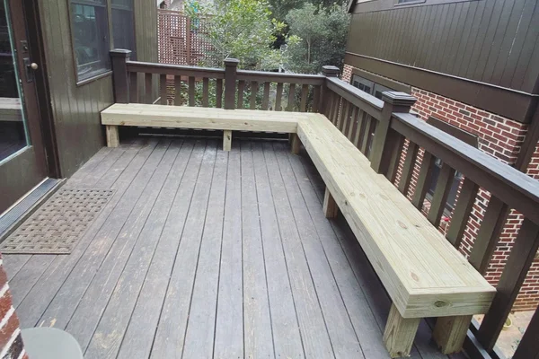 Custom L-shaped pressure-treated bench built into deck railing