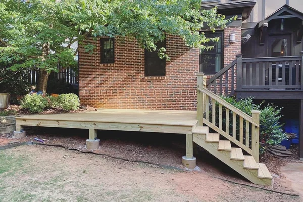 New floating deck with pressure-treated framing on concrete pier footings, side staircase with railing