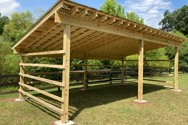 Custom post-and-beam run-in shed with pitched roof and horizontal board rails