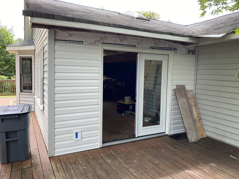 Patio door replacement in progress with one leaf of the new French door set in the opening