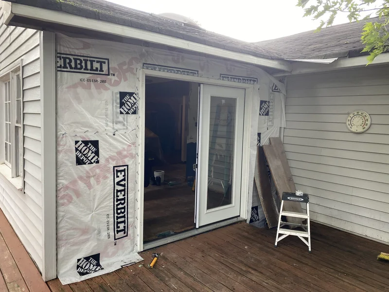 New French patio door set in place with house wrap around the opening before new siding