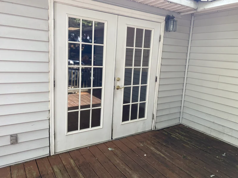 Original French patio door with brass hardware and aged siding before replacement