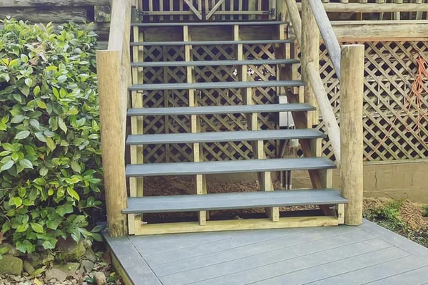 Composite staircase with lattice skirting, log-post handrails, and gated deck entrance