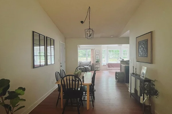 Renovated living area with hardwood floors, cedar beam, and modern pendant light