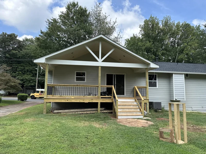 Completed covered porch with painted gable, black iron balusters, and new stair run