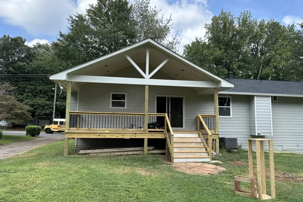 Completed covered porch with painted gable, black iron balusters, and new stair run