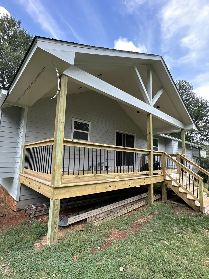 Finished covered porch from the corner showing the gable overhang, vaulted white ceiling, and railing system