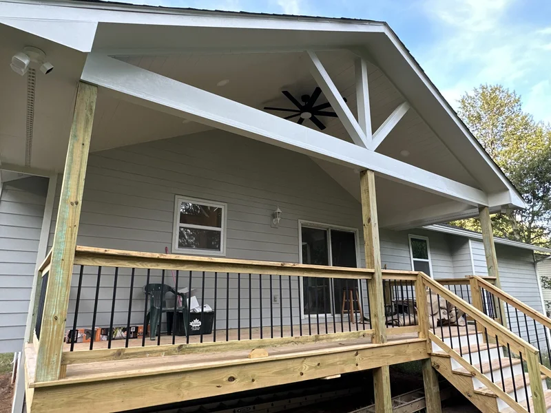 Porch ceiling detail with white plank vaulted ceiling, ceiling fan, and decorative gable truss