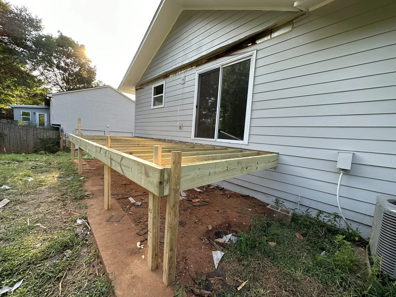 New pressure-treated deck framing on posts along the house