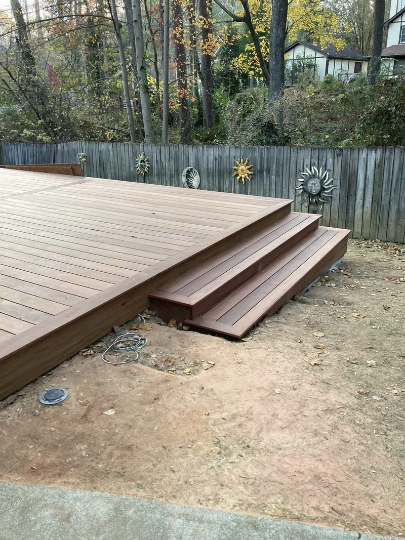 Finished hardwood deck surface and corner steps along the fenced backyard