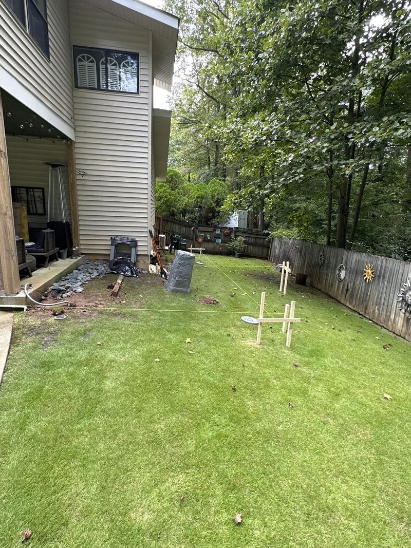 Backyard lawn with layout strings and stakes marking the new deck footprint