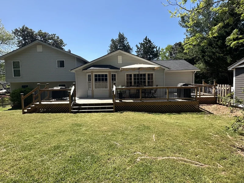 Completed deck spanning the full back of the house with railings, lattice skirting, and outdoor furniture