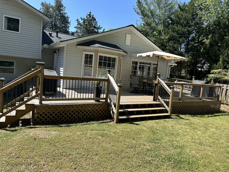 Finished deck with dual stair runs, black iron balusters, and lattice skirting