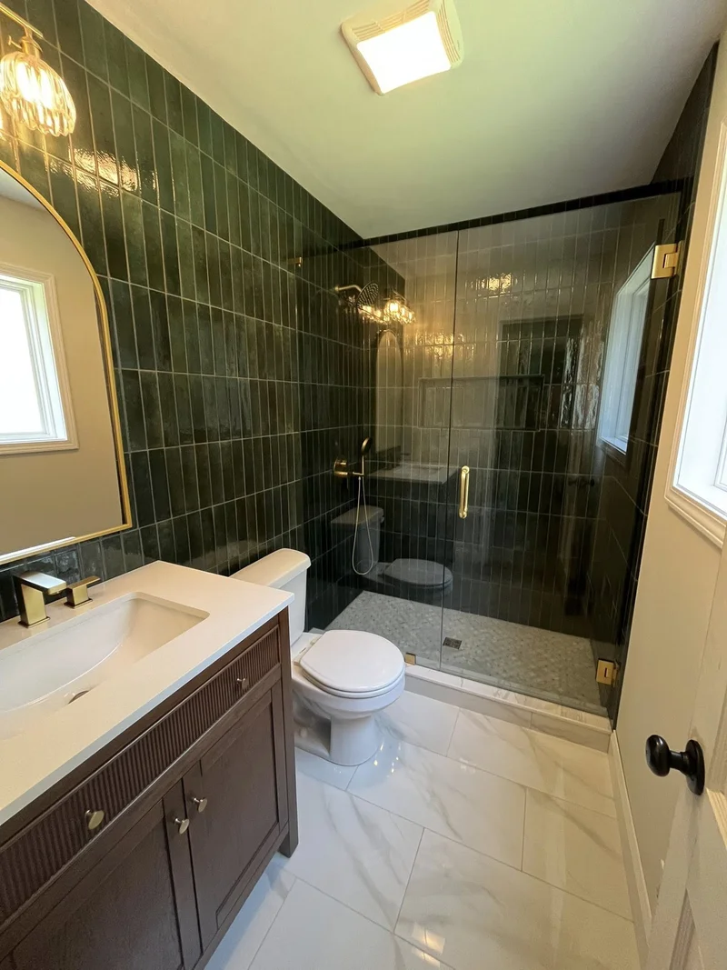 Renovated bathroom with forest green zellige tile and brushed gold fixtures
