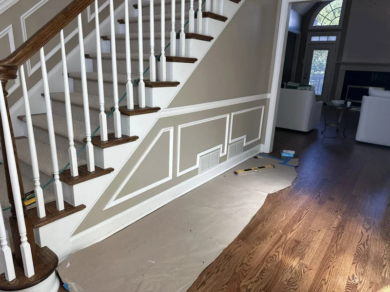 Picture frame wainscoting running the full length of the staircase wall with white turned balusters