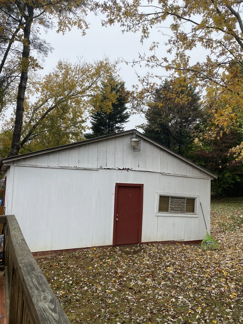 Rear of the garage before renovation, weathered siding and old door